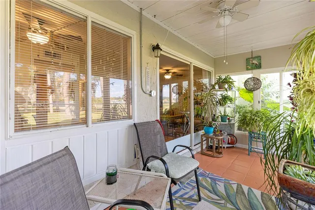 a balcony with table and chairs and potted plants