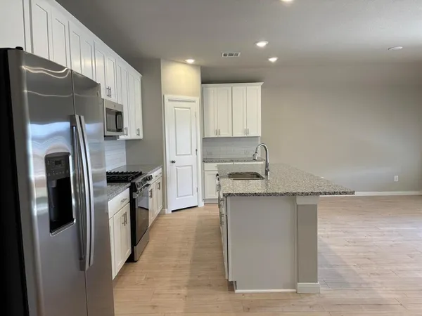 a kitchen with stainless steel appliances granite countertop a sink a stove a refrigerator and cabinets