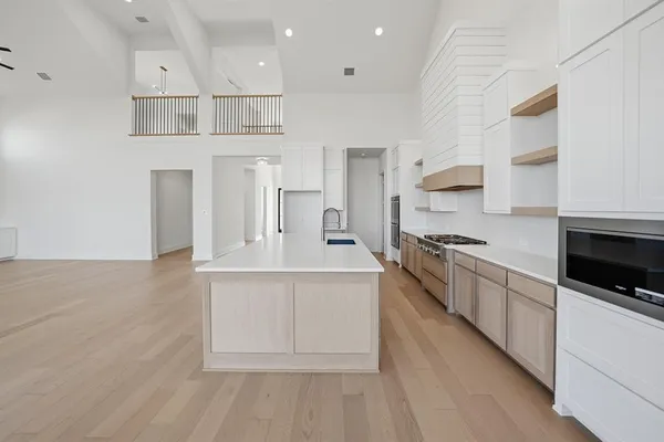 a large white kitchen with kitchen island a sink stainless steel appliances and cabinets