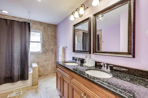a bathroom with a granite countertop double vanity sink and a mirror
