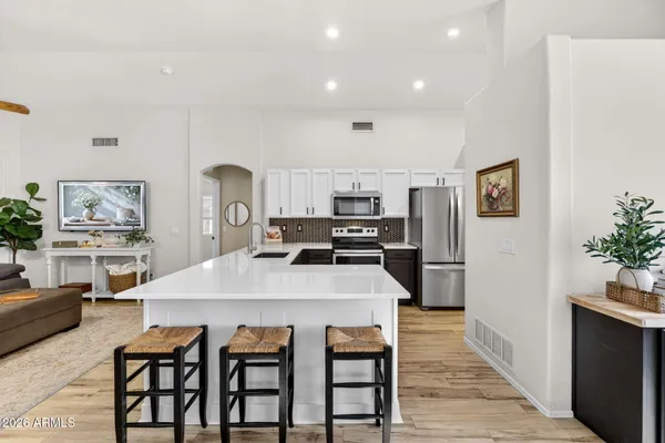 a kitchen with stainless steel appliances a stove a sink dishwasher a refrigerator white cabinets and wooden floor