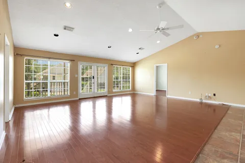 a view of an empty room with wooden floor and a window