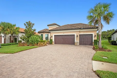 a front view of a house with a garden and palm trees