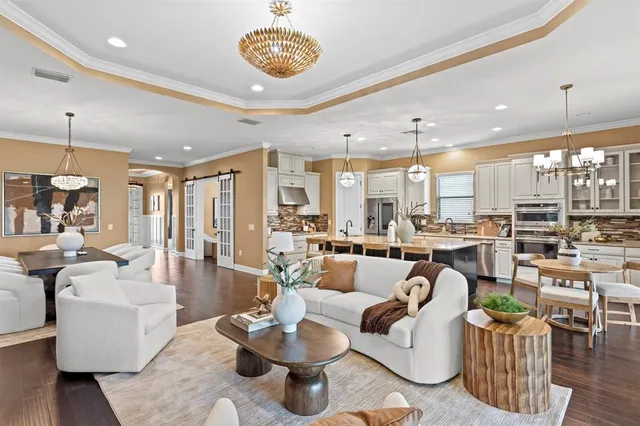 a living room with furniture kitchen view and a chandelier