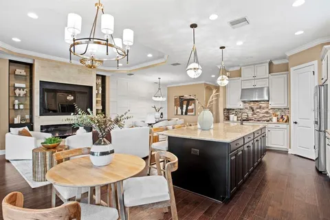 a kitchen with stainless steel appliances granite countertop a refrigerator a oven a sink a dining table and chairs with wooden floor