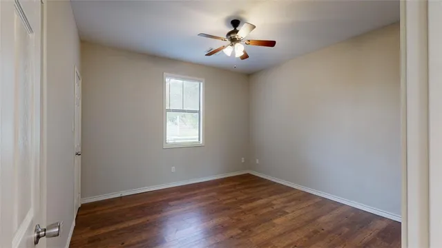 an empty room with wooden floor and ceiling fan