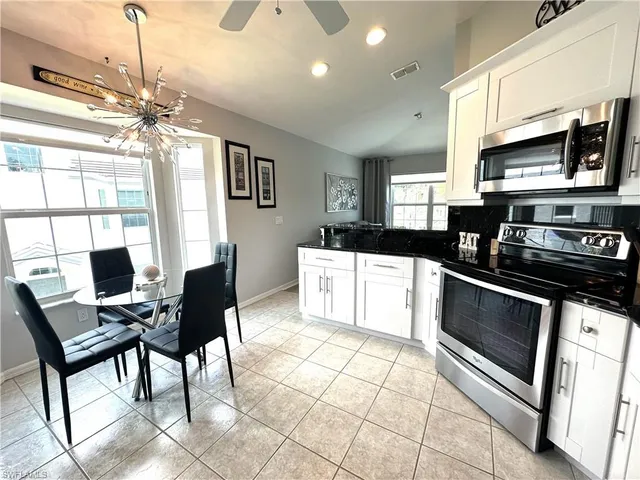 a kitchen with stainless steel appliances granite countertop a stove top oven a sink dishwasher a dining table and chairs with wooden floor