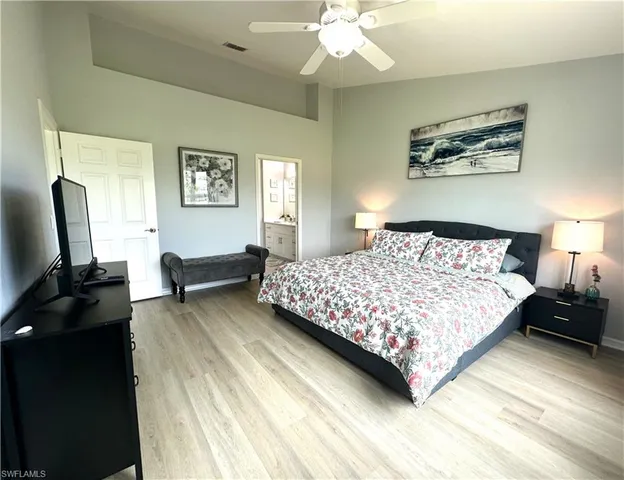 a bedroom with a bed a computer on the desk and a dresser