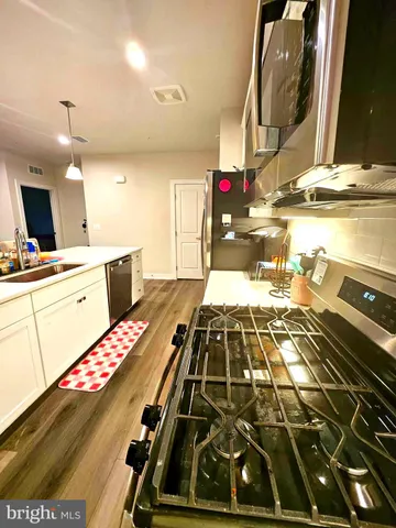 a large white kitchen with wooden floor
