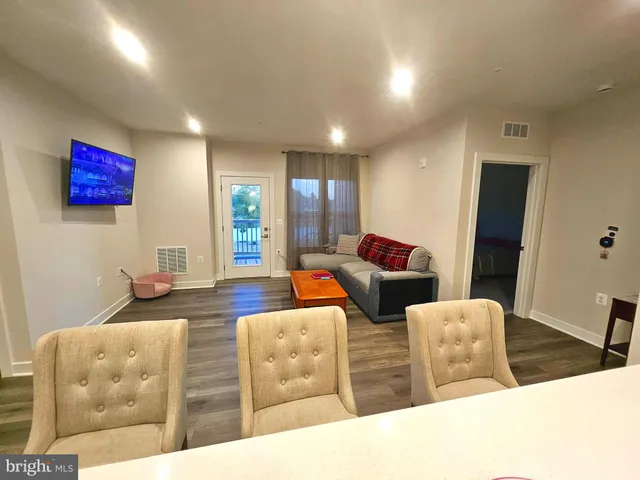 a kitchen with stainless steel appliances kitchen island granite countertop a stove top oven a sink dishwasher and white cabinets with wooden floor