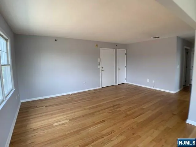 a view of empty room with wooden floor and fan
