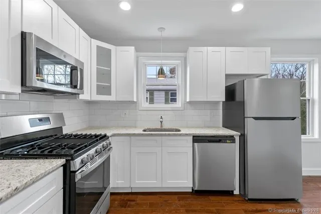 a kitchen with stainless steel appliances granite countertop a stove a refrigerator and a sink