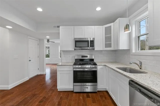 a kitchen with stainless steel appliances granite countertop a stove a sink and a microwave