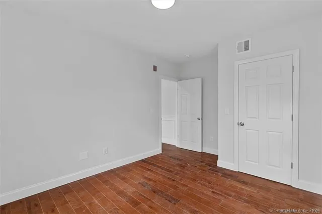 a view of an empty room with wooden floor and closet