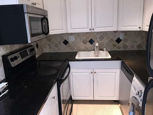 a kitchen with white cabinets and black appliances