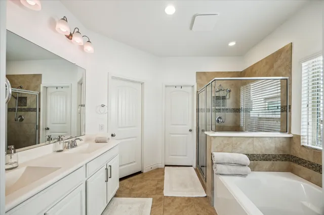 a spacious bathroom with a double vanity sink large mirror and a bathtub