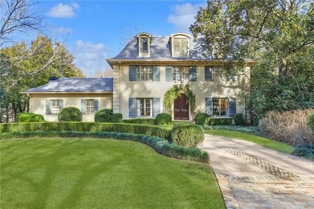 a view of a house next to a big yard and large trees