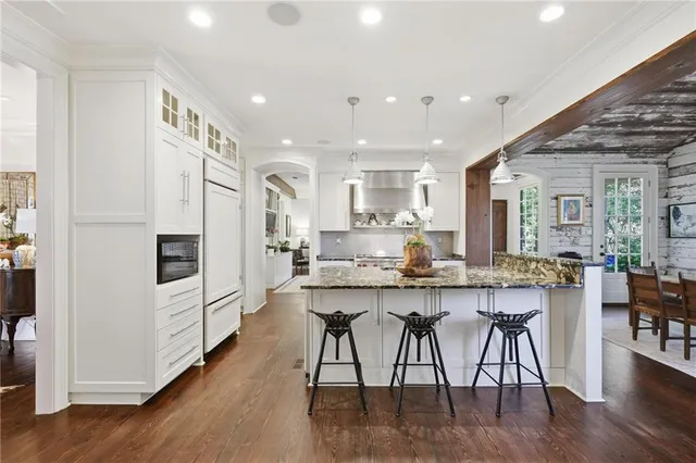 a kitchen with stainless steel appliances granite countertop a table chairs stove a refrigerator and cabinets