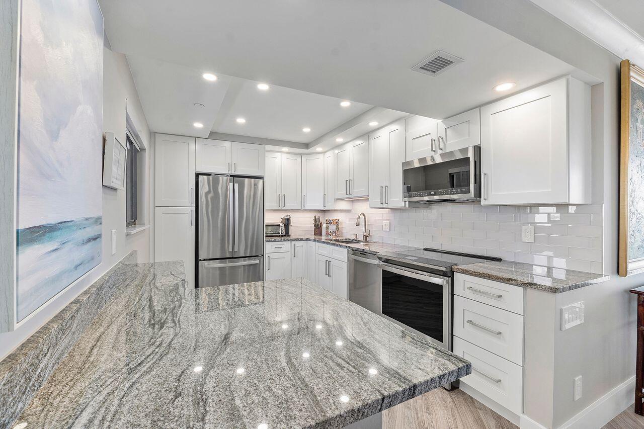 200 Ocean Trail Way, Unit 602 Jupiter, FL 33477 - Photo 11 of 50 a kitchen with kitchen island a sink stainless steel appliances and cabinets