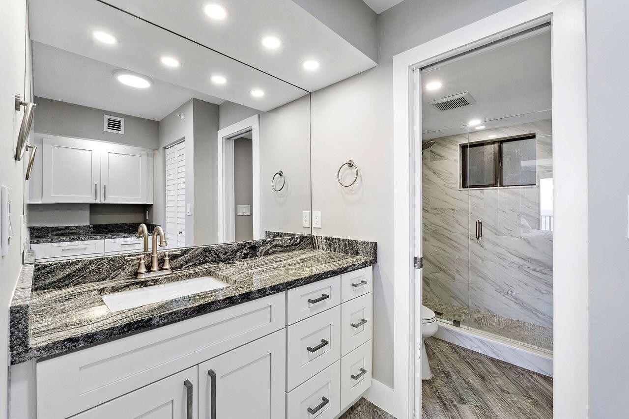 200 Ocean Trail Way, Unit 602 Jupiter, FL 33477 - Photo 23 of 50 a bathroom with a granite countertop sink a double vanity and mirror