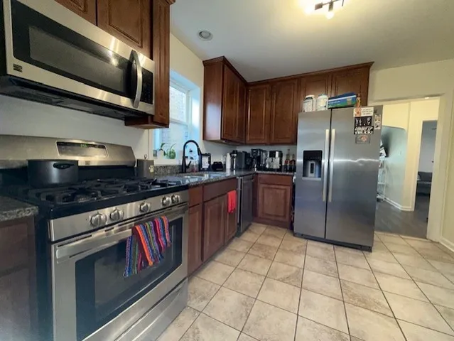 a kitchen with stainless steel appliances granite countertop a stove a sink and a microwave