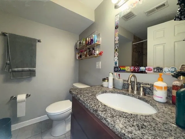 a bathroom with a granite countertop sink a mirror and a toilet