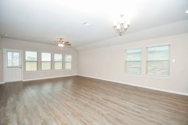 an empty room with wooden floor chandelier and windows