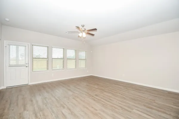 an empty room with wooden floor and ceiling fan