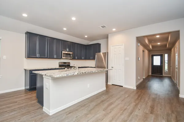 a kitchen with stainless steel appliances granite countertop a stove cabinets and wooden floor