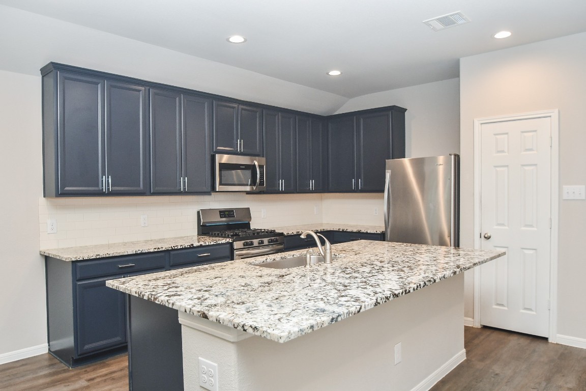 17811 Chartertree Lane Tomball, TX 77377 - Photo 8 of 32 a kitchen with granite countertop a sink a stove and a wooden cabinets