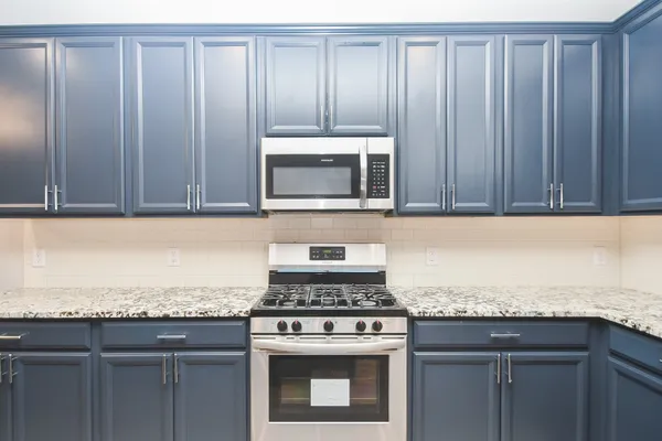 a kitchen with granite countertop stainless steel appliances wooden cabinets and a stove top oven