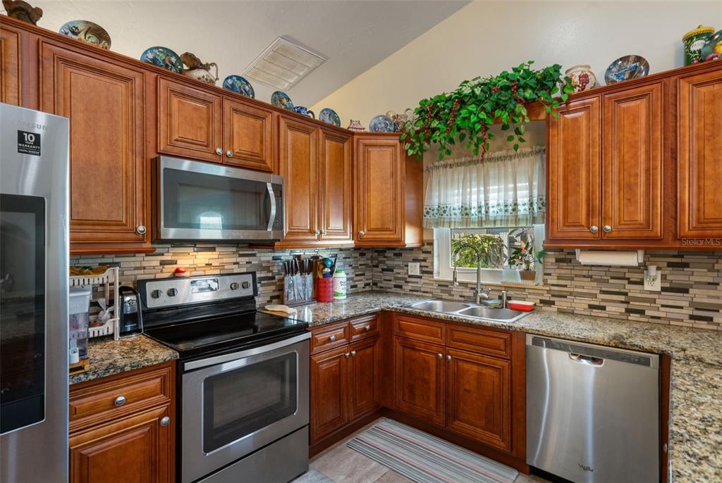 10421 Templewood Court Spring Hill, FL 34608 - Photo 13 of 63 a kitchen with kitchen island granite countertop a sink and a stove top oven