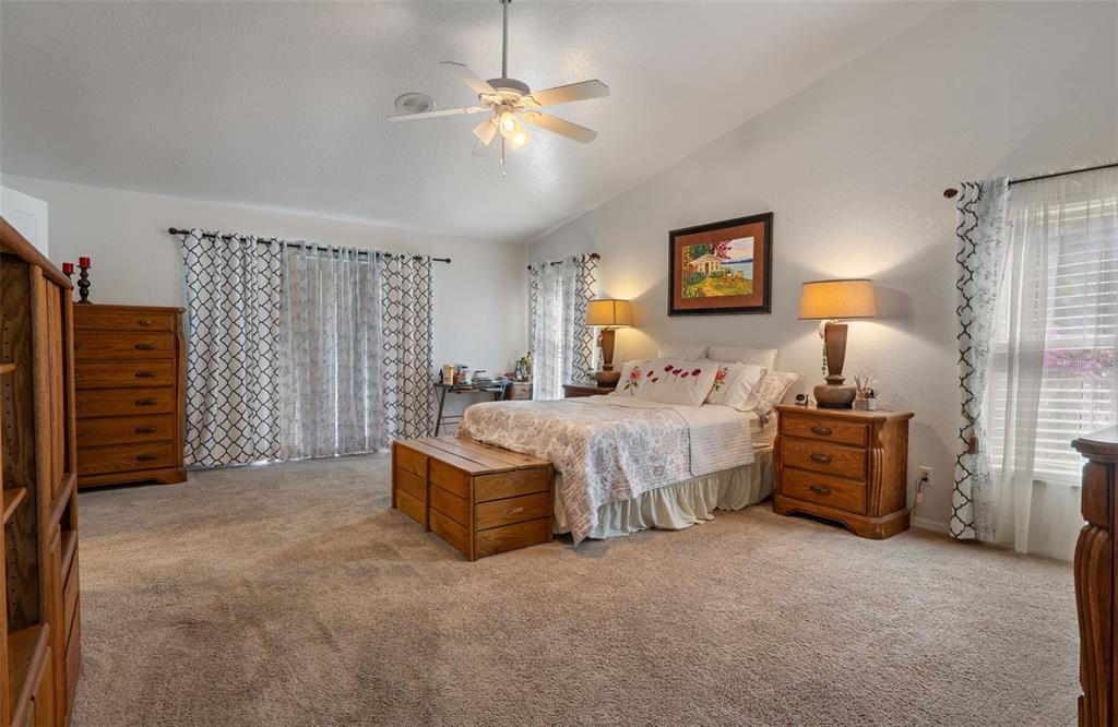 10421 Templewood Court Spring Hill, FL 34608 - Photo 26 of 63 a spacious bedroom with a bed and a chandelier