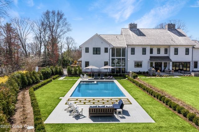 a view of a house with swimming pool lawn chairs and a yard
