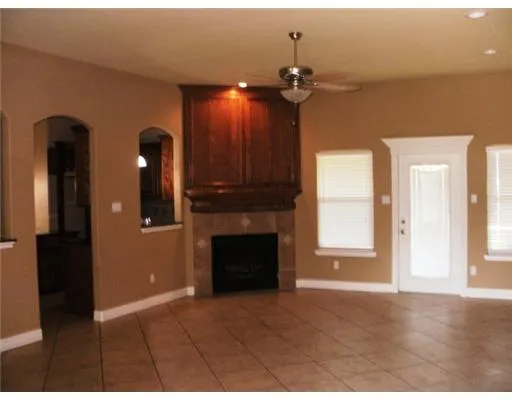 a view of an empty room with chandelier fan and fire place