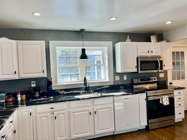 a kitchen with granite countertop a refrigerator and a stove top oven