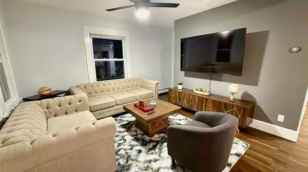 a living room with couches and a flat screen tv with kitchen view