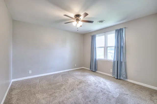 an empty room with windows and ceiling fan