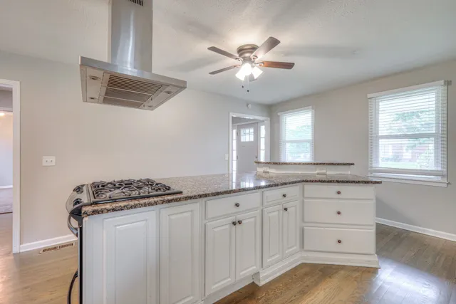 a kitchen with granite countertop white cabinets and window