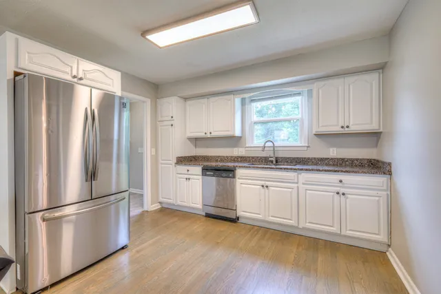 a kitchen with granite countertop stainless steel appliances a refrigerator sink and cabinets