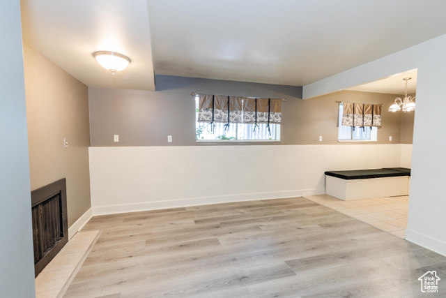 167 East 100 North, Unit B Logan, UT 84321 - Photo 18 of 18 Unfurnished dining area with light wood-type flooring, a chandelier, and a fireplace
