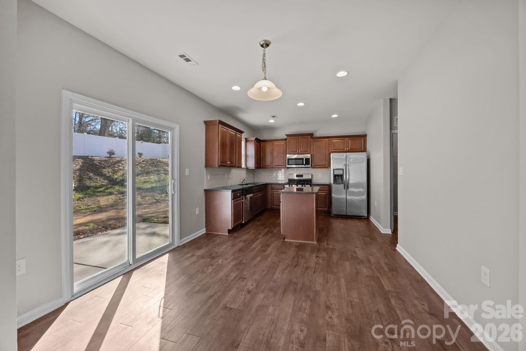 116 Rippling Water Drive Mount Holly, NC 28120 - Photo 13 of 48 a open kitchen with a refrigerator a stove top oven a sink and a large window