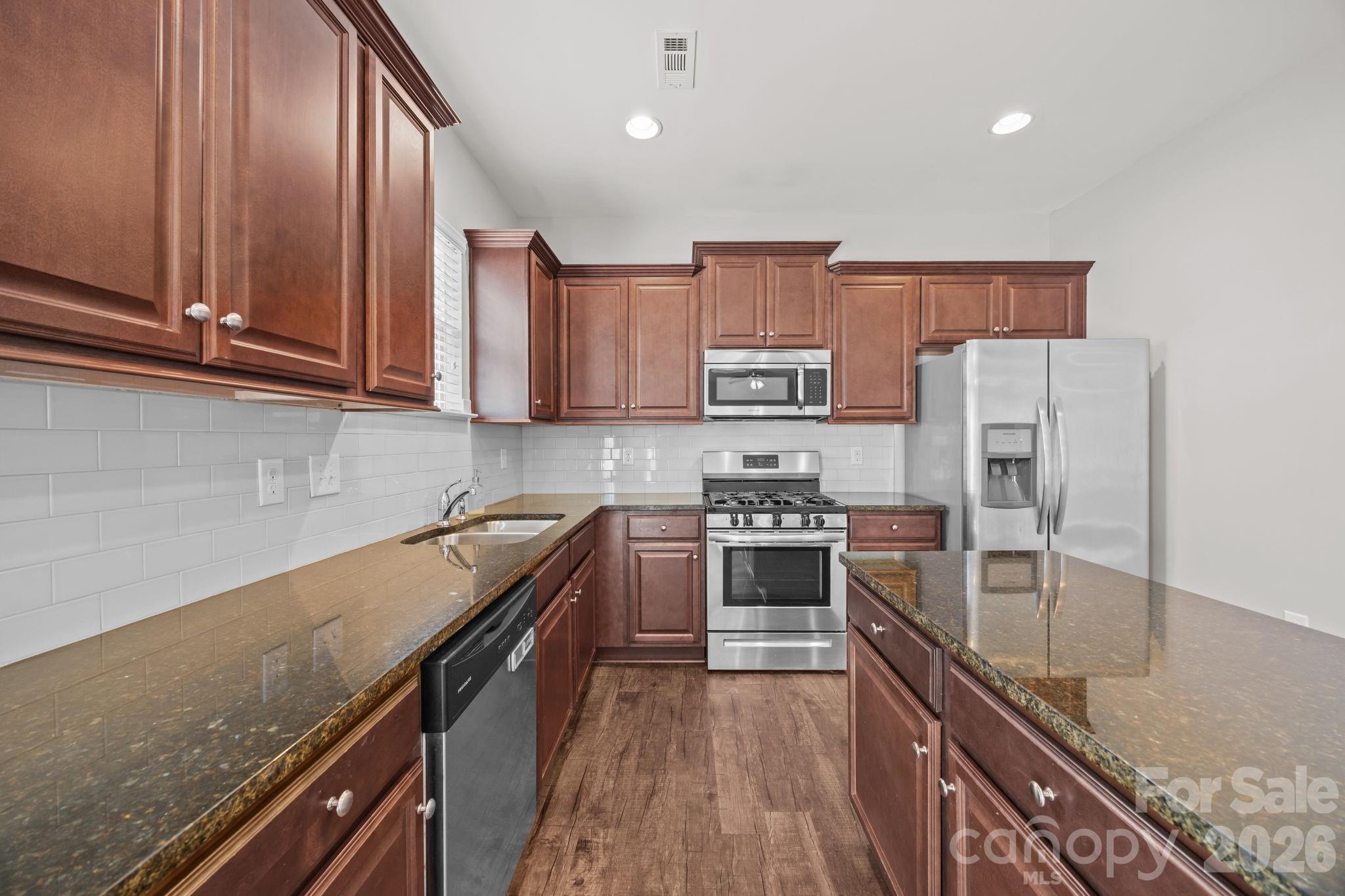 116 Rippling Water Drive Mount Holly, NC 28120 - Photo 16 of 48 a kitchen with stainless steel appliances granite countertop a stove top oven a sink and dishwasher