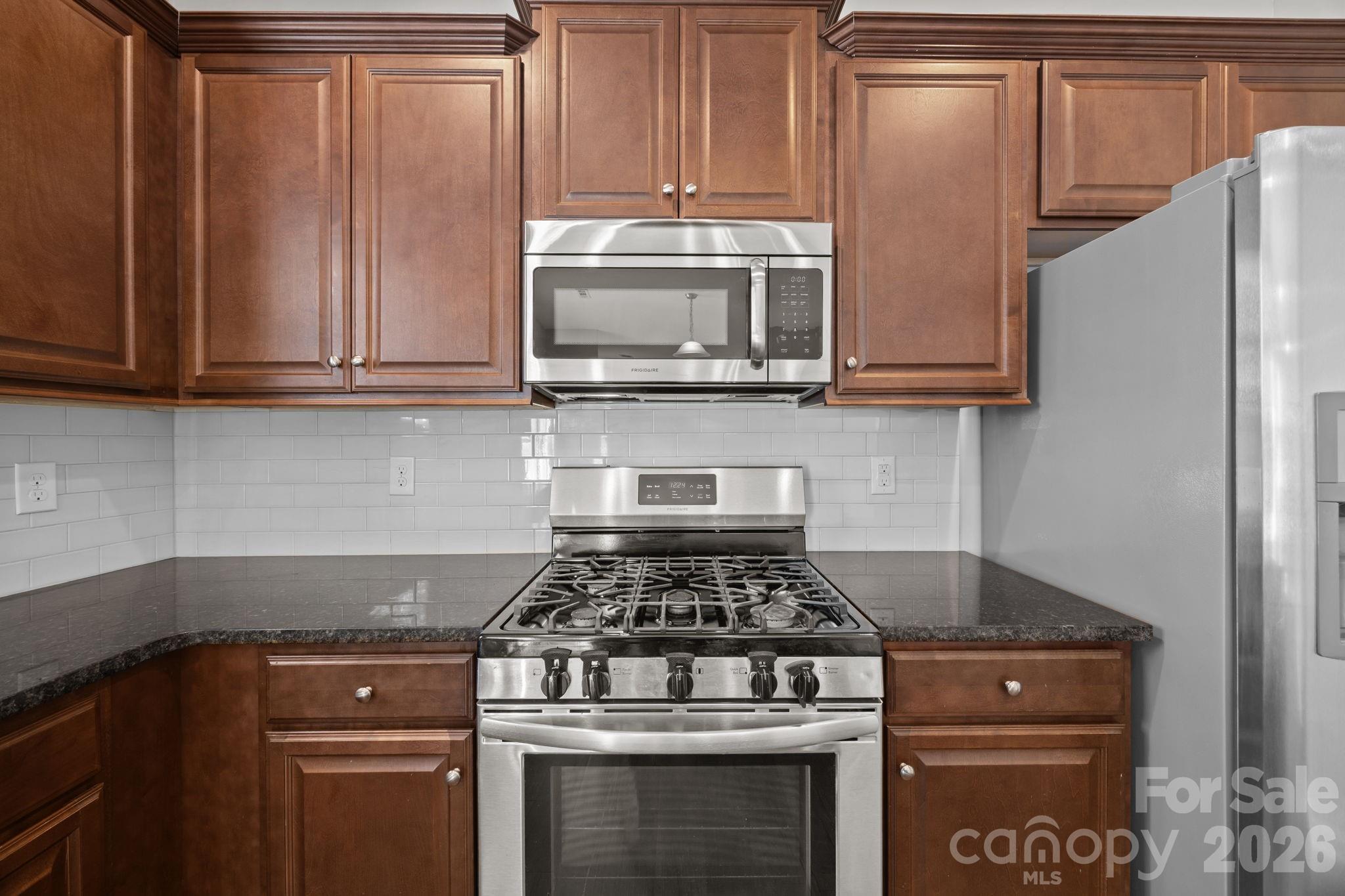 116 Rippling Water Drive Mount Holly, NC 28120 - Photo 18 of 48 a kitchen with granite countertop a stove and a microwave