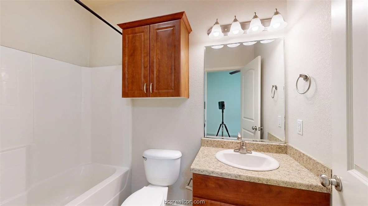 4453-4455 Reveille Road College Station, TX 77845 - Photo 29 of 37 a bathroom with a granite countertop sink and a mirror with toilet