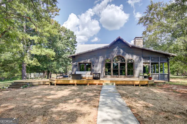 a view of a backyard with table and chairs potted plants and large tree