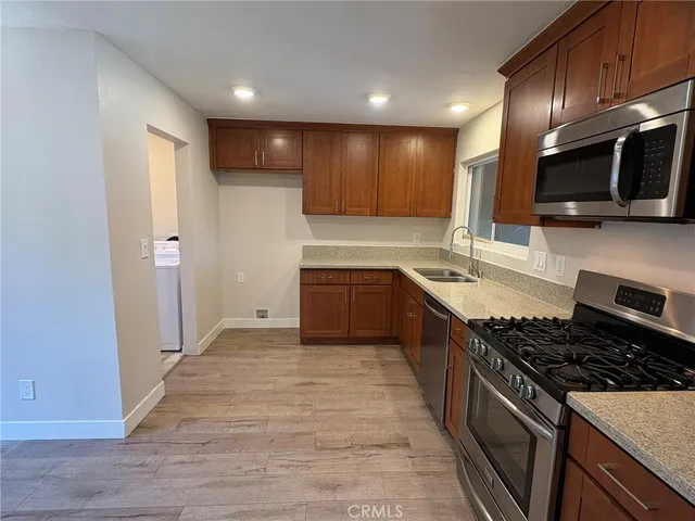 a large kitchen with stainless steel appliances granite countertop a stove a sink and a microwave