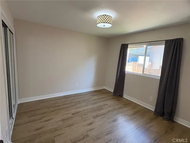 an empty room with wooden floor and window