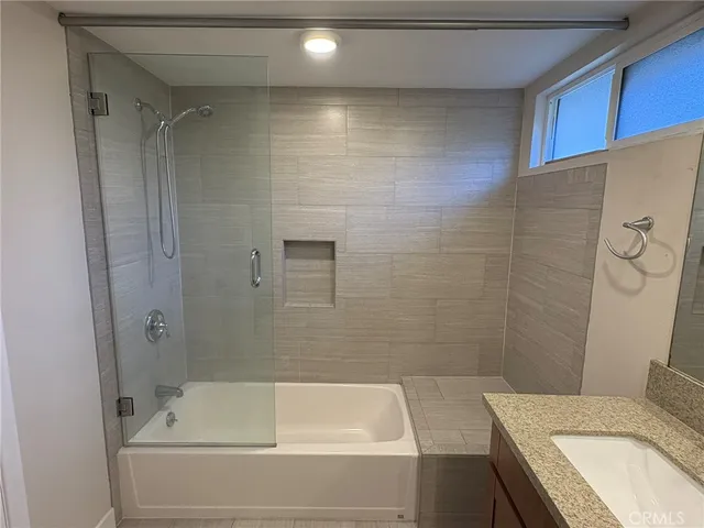 a bathroom with a granite countertop bathtub shower sink vanity and toilet