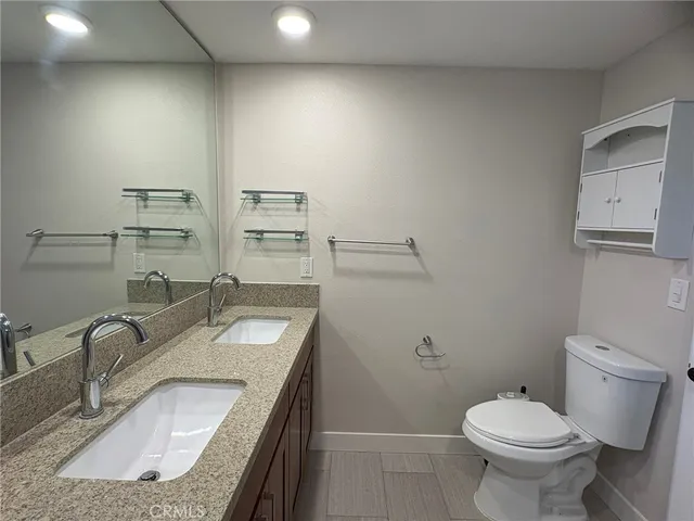 a bathroom with a granite countertop sink a toilet and a mirror